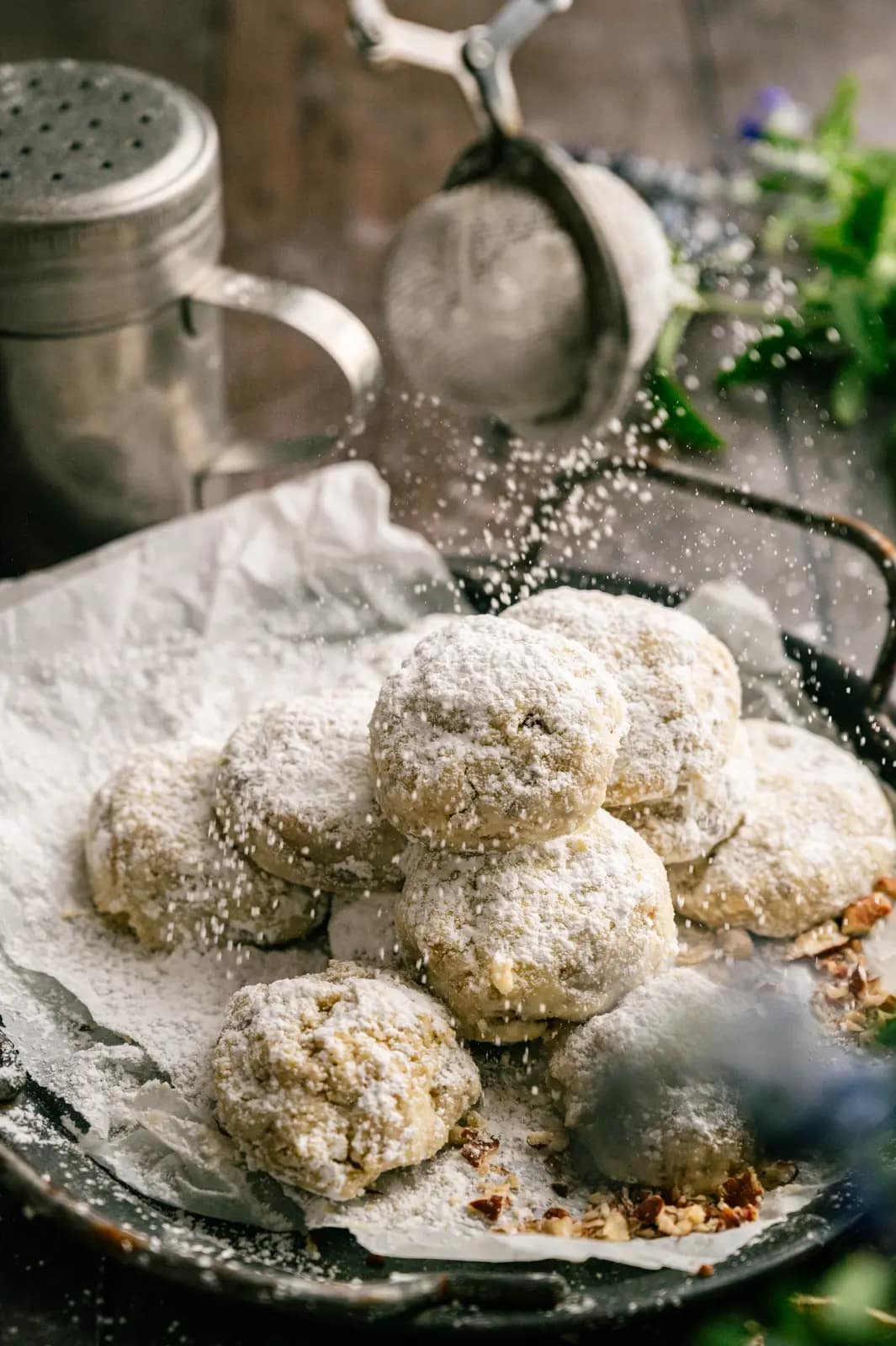 Powdered sugar falling over a pile of pecan snowball cookies.