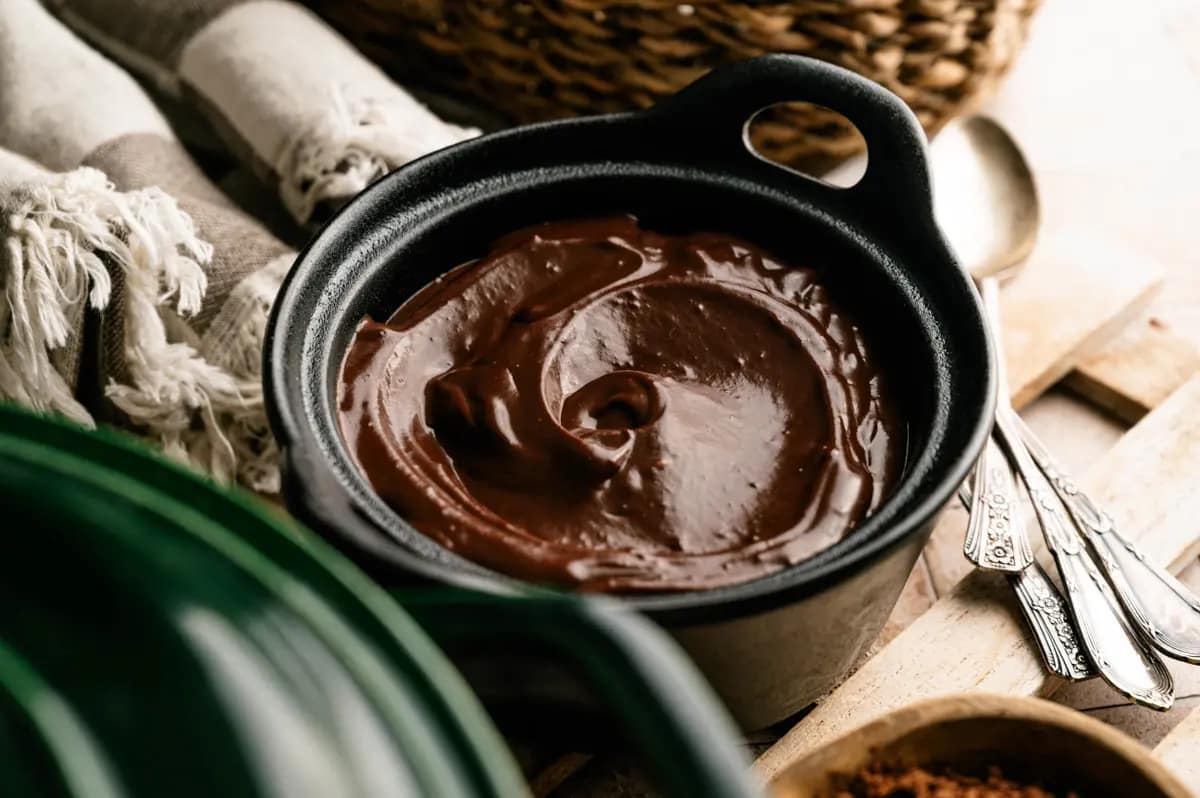 Classic homemade chocolate pudding served in a black bowl on a weathered table