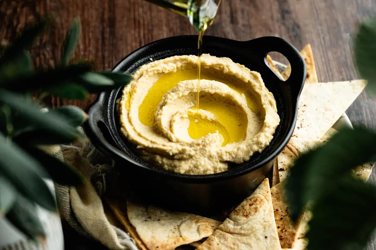 Homemade hummus served with pita bread on a rustic wooden table