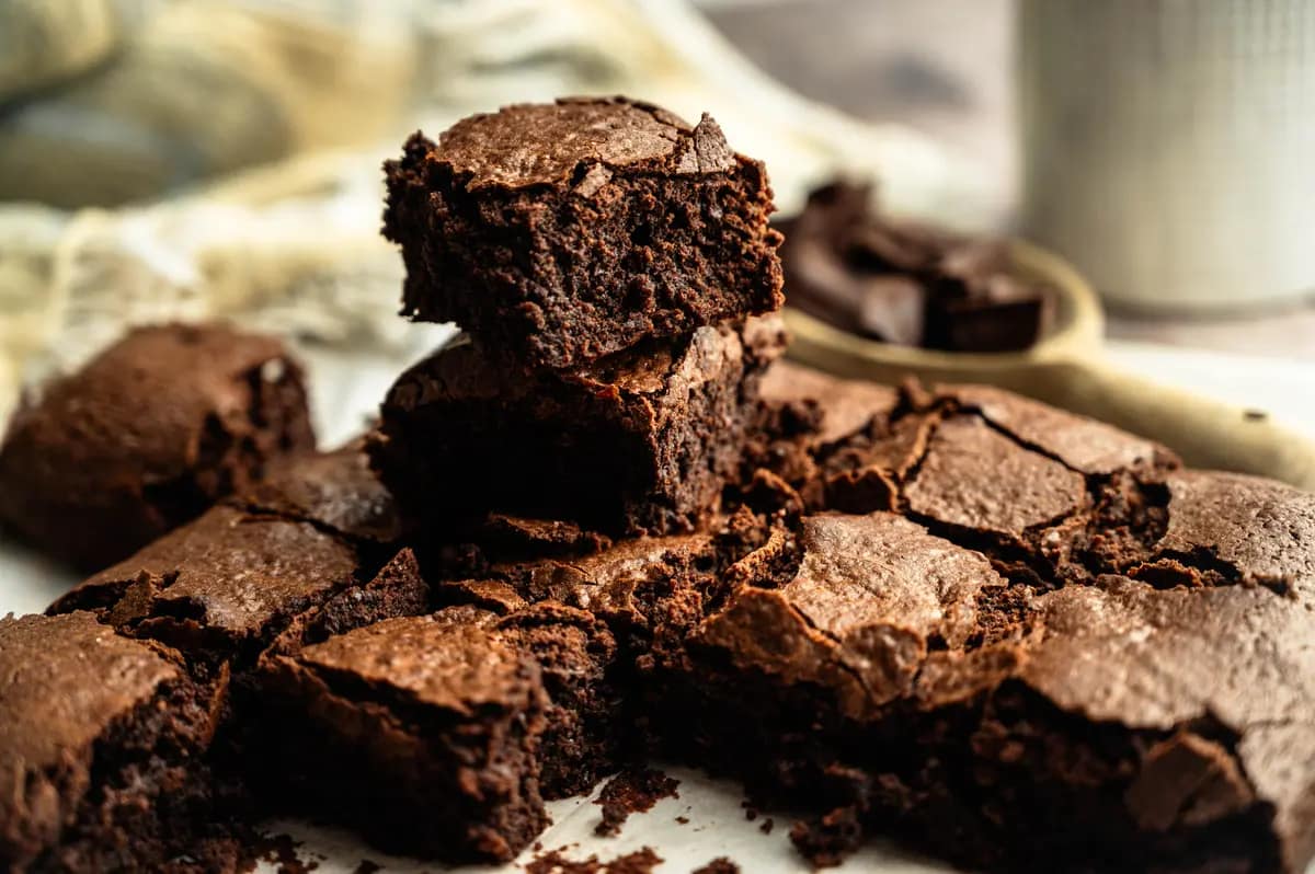 Stacked brownie squares showing dark chocolate centers and thin crackled tops.