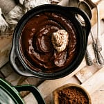 Silky chocolate pudding topped with whipped cream and cocoa in a dark bowl