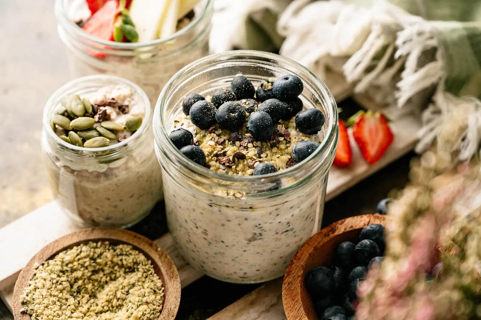Two jars of overnight oats topped with blueberries, seeds, and fruit