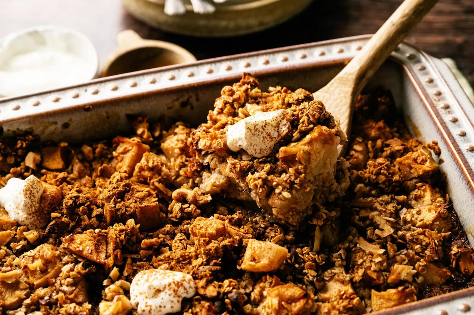 Apple oatmeal breakfast bake being scooped from a ceramic baking dish