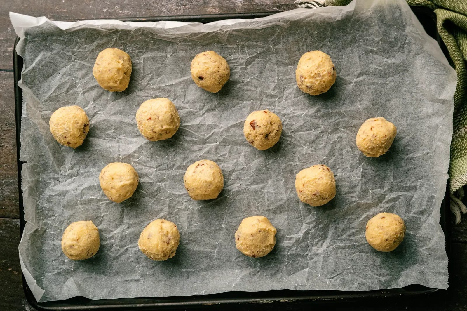 Round portions of pecan cookie dough on a parchment-lined baking tray.