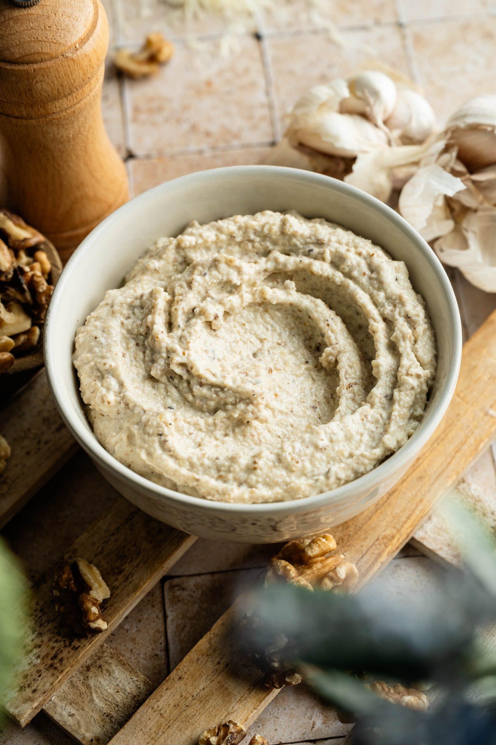 Salsa di Noci sauce in a bowl on a wooden board with walnuts and garlic.