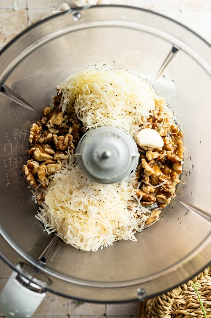 Walnuts, grated cheese and garlic in a food processor bowl.