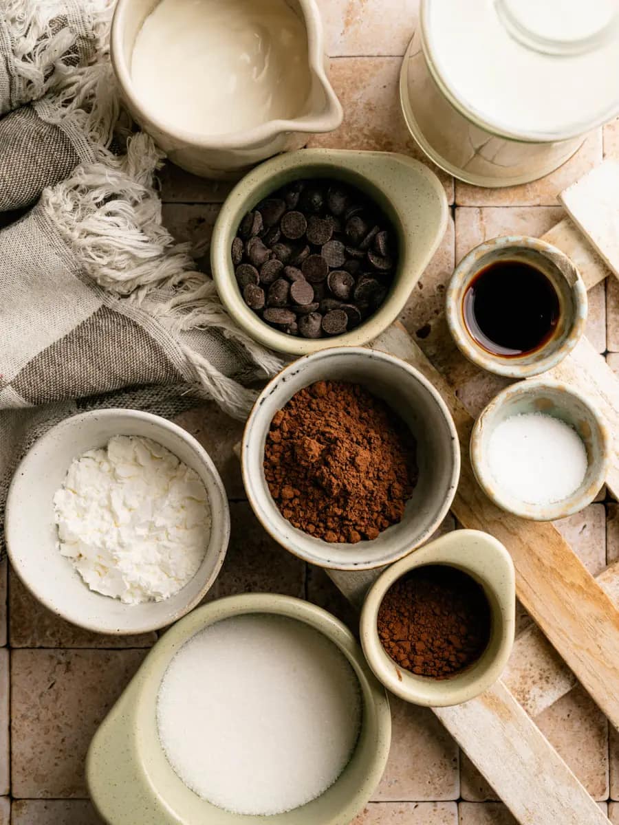 Milk, cocoa powder, sugar, chocolate, and other ingredients for homemade chocolate pudding