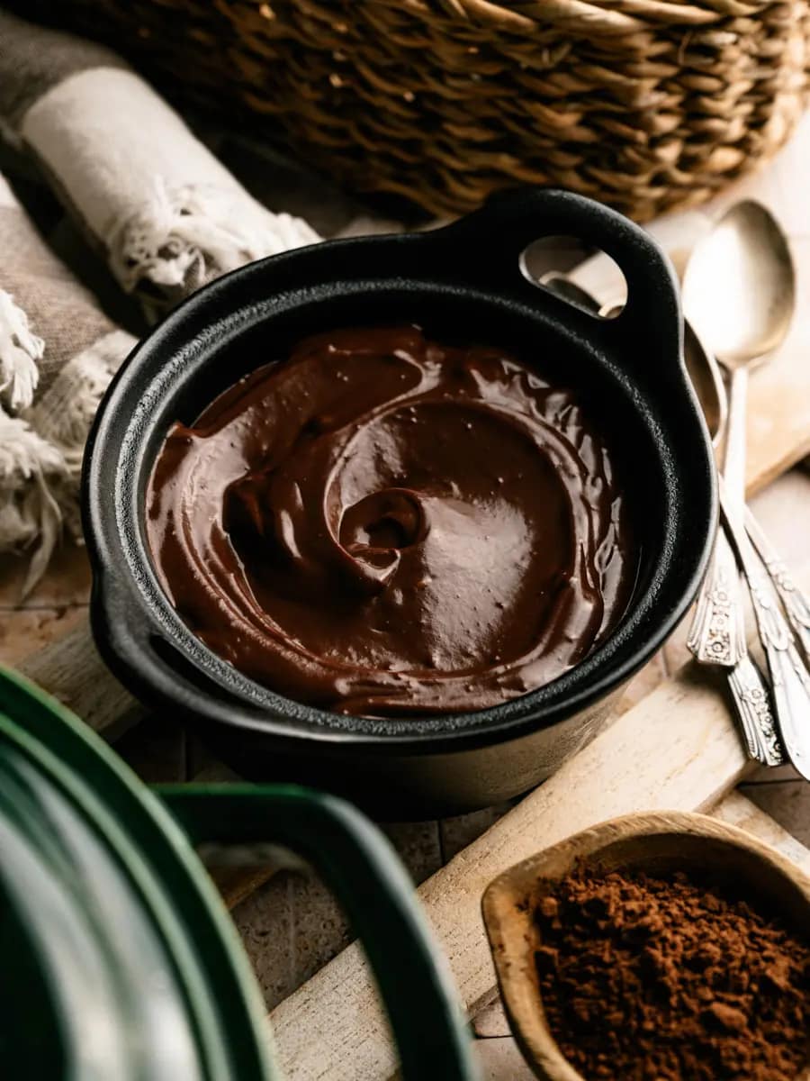 Homemade chocolate pudding in a dark ceramic bowl on a rustic table